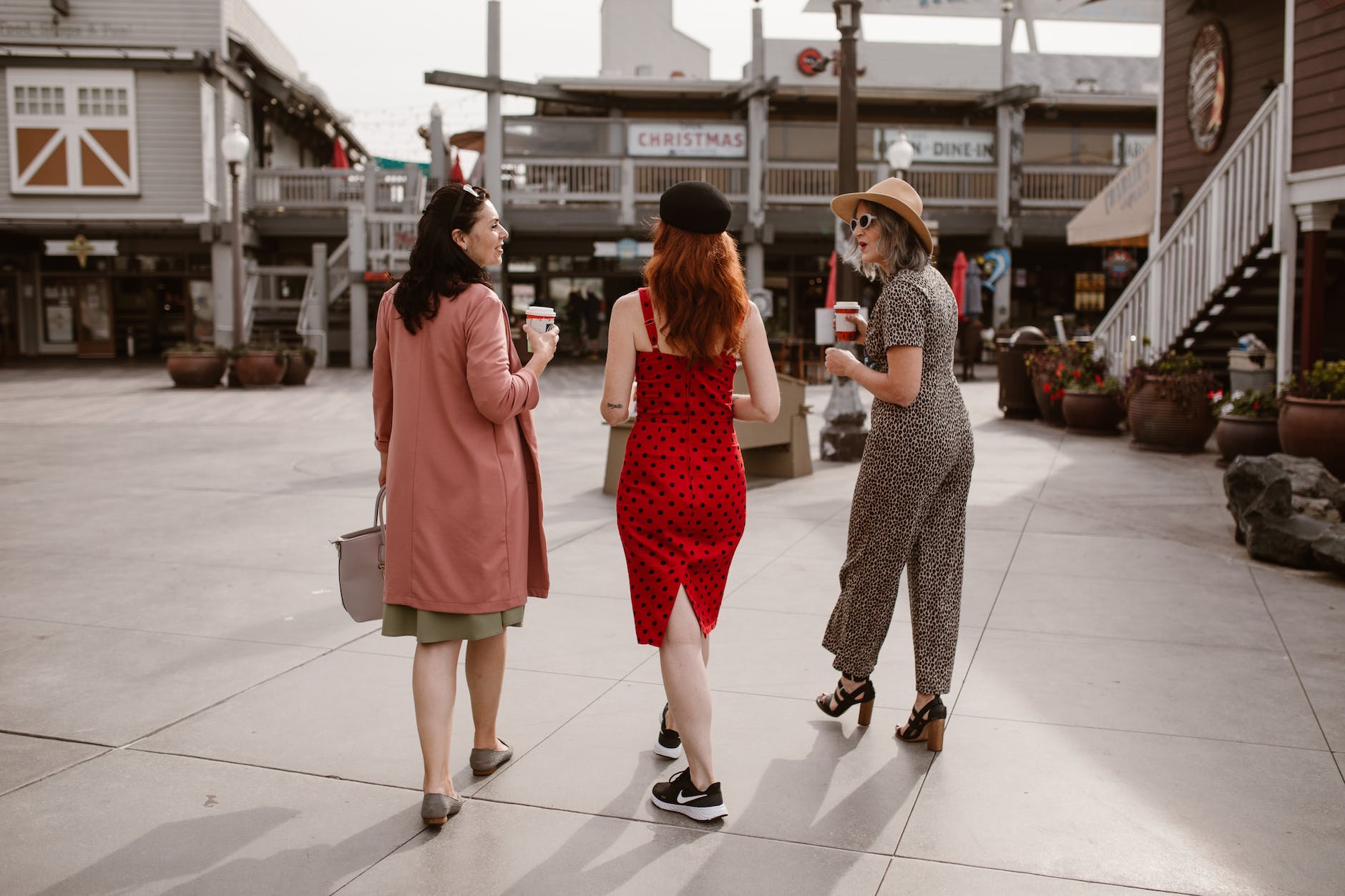 elegant women walking on street and drinking takeaway coffee