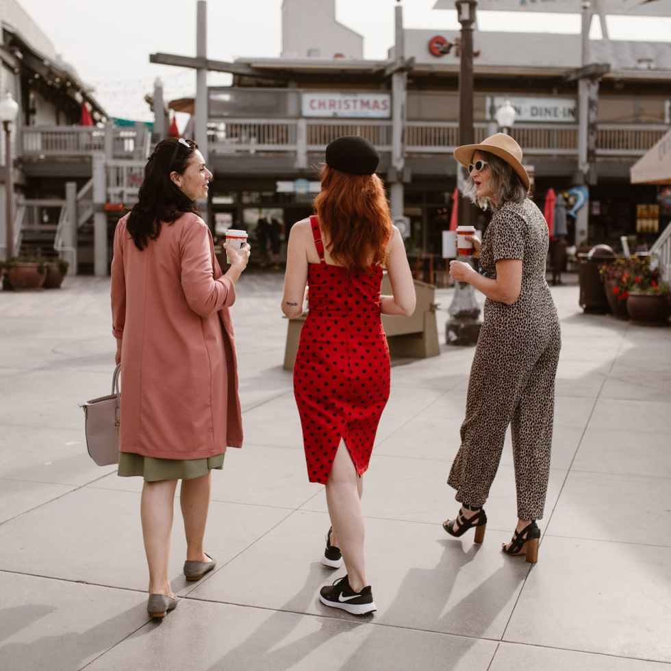 elegant women walking on street and drinking takeaway coffee