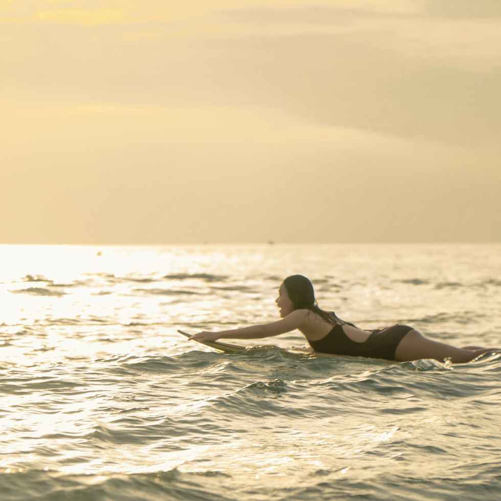 woman swimming on surfboard on sea shore