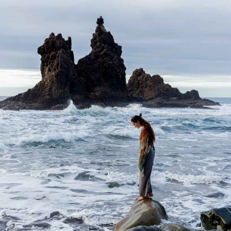 lonely woman standing on rocky coast